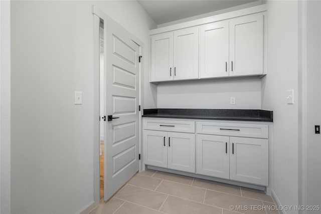 2332 E 135th Dr S, Bixby, OK 74008 - kitchen featuring dark countertops, light tile patterned floors, white cabinets, and baseboards