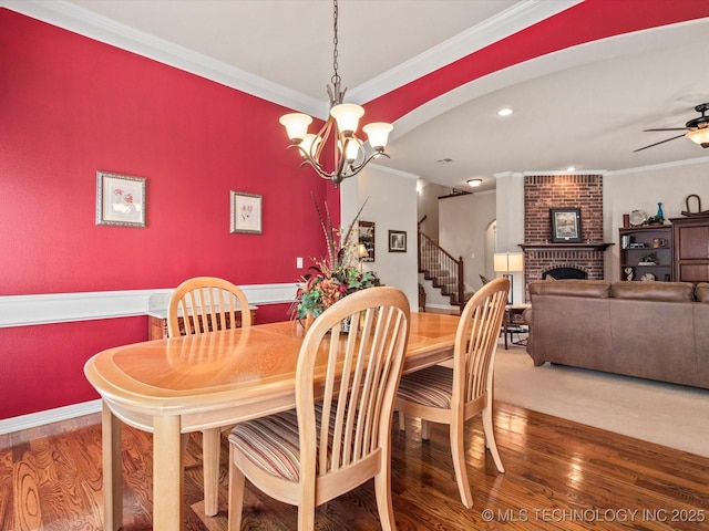 5816 Woodland Rd, Bartlesville, OK 74006 - dining space with wood finished floors, a brick fireplace, stairs, ornamental molding, and a chandelier