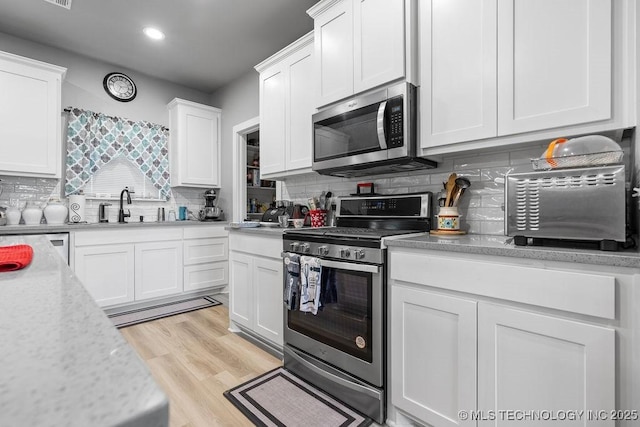 40 Wilson Pkwy, Durant, OK 74701 - kitchen with stainless steel appliances, light countertops, white cabinets, backsplash, and recessed lighting