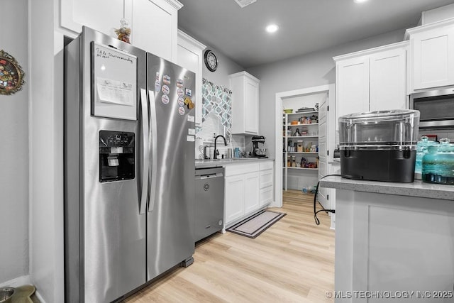 40 Wilson Pkwy, Durant, OK 74701 - kitchen with stainless steel appliances, a sink, white cabinets, light countertops, and light wood-style flooring