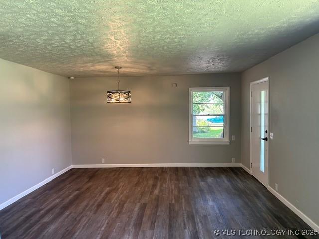 111 E 13th Pl, Claremore, OK 74017 - unfurnished room featuring dark wood-style floors, a textured ceiling, and baseboards