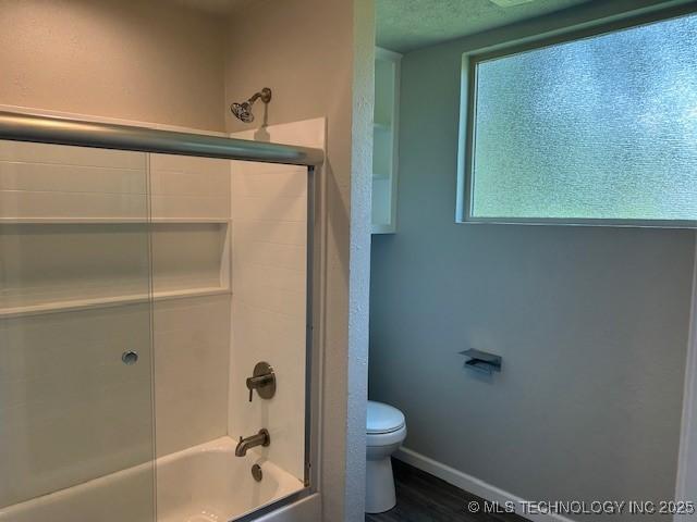 111 E 13th Pl, Claremore, OK 74017 - full bathroom featuring toilet, shower / bath combination with glass door, wood finished floors, and baseboards