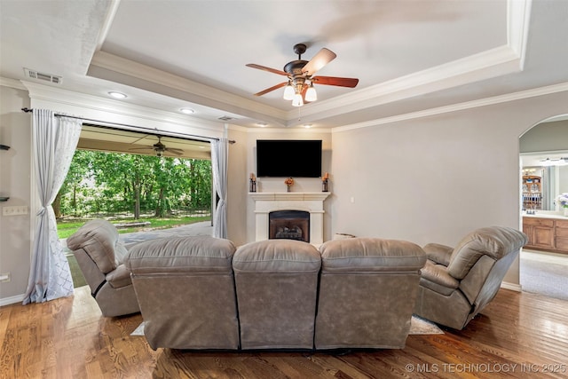 18932 Spring Creek Ln, Claremore, OK 74017 - living area with a tray ceiling, ceiling fan, wood finished floors, crown molding, and arched walkways