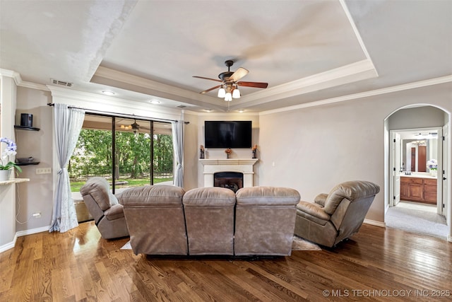 18932 Spring Creek Ln, Claremore, OK 74017 - living room with a tray ceiling, a ceiling fan, wood finished floors, arched walkways, and crown molding