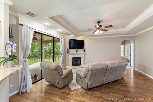 18932 Spring Creek Ln, Claremore, OK 74017 - living room with a raised ceiling, ceiling fan, ornamental molding, wood finished floors, and arched walkways