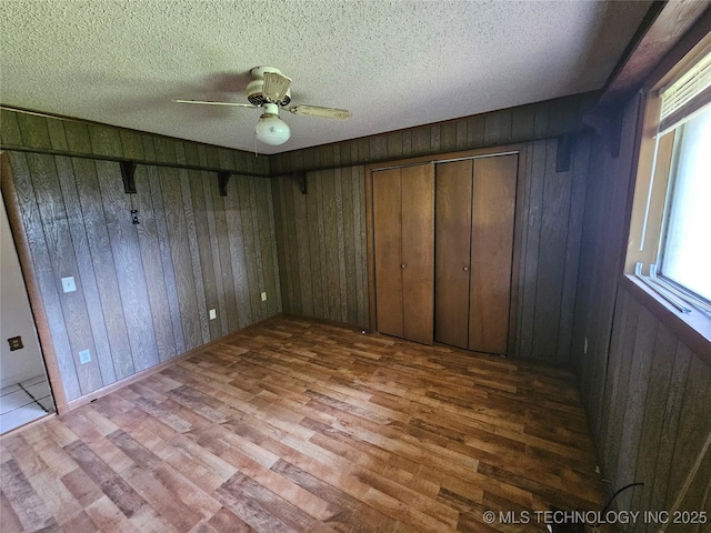 2700 N Witte St, Poteau, OK 74953 - unfurnished bedroom with wood finished floors, wood walls, and ceiling fan