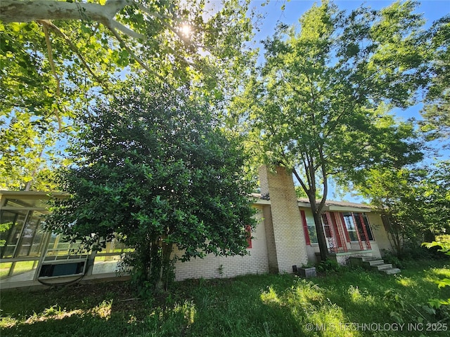 2700 N Witte St, Poteau, OK 74953 - view of property exterior featuring a sunroom, brick siding, and a chimney