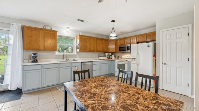 4964 SE Brookline Dr, Bartlesville, OK 74006 - kitchen with appliances with stainless steel finishes, light tile patterned flooring, decorative light fixtures, and brown cabinetry