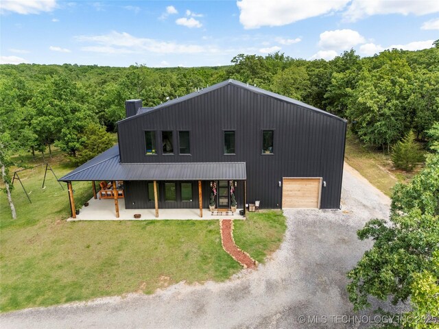 8562 Adams Creek Rd, Beggs, OK 74421 - view of front of house featuring gravel driveway, a front lawn, covered porch, and a wooded view