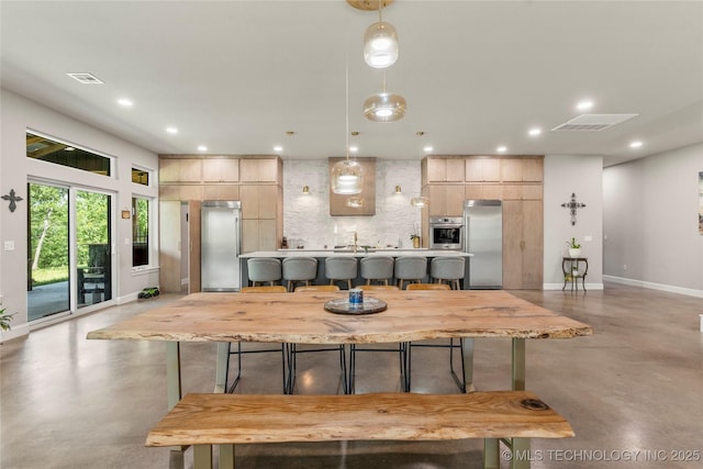 8562 Adams Creek Rd, Beggs, OK 74421 - kitchen featuring concrete floors, stainless steel appliances, a breakfast bar area, tasteful backsplash, and light countertops