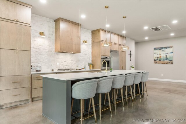 8562 Adams Creek Rd, Beggs, OK 74421 - kitchen featuring light brown cabinetry, concrete floors, stainless steel appliances, a center island with sink, and a kitchen breakfast bar