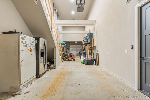 8562 Adams Creek Rd, Beggs, OK 74421 - garage featuring freestanding refrigerator, stainless steel fridge with ice dispenser, and a garage door opener
