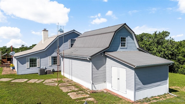 168 Murray Ln, Strang, OK 74367 - back of house with a lawn, metal roof, a chimney, central air condition unit, and a gambrel roof