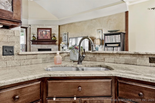 3501 W Gary St S, Broken Arrow, OK 74012 - kitchen featuring light stone counters, vaulted ceiling, dark brown cabinetry, a fireplace, and open floor plan