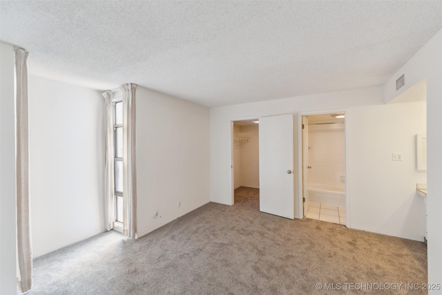 410 W 7th St Unit 241, Tulsa, OK 74119 - unfurnished bedroom with carpet flooring, a textured ceiling, a spacious closet, and ensuite bathroom