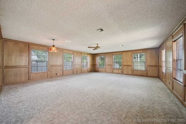3218 S Kingston Ave, Tulsa, OK 74135 - empty room featuring healthy amount of natural light, light colored carpet, wooden walls, a textured ceiling, and ceiling fan