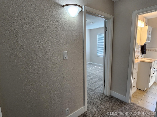 307 N W St, Mcalester, OK 74501 - hall with light carpet, a sink, light tile patterned floors, and baseboards
