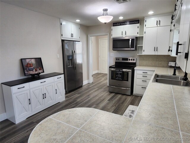 307 N W St, Mcalester, OK 74501 - kitchen with stainless steel appliances, a sink, dark wood-style floors, white cabinets, and recessed lighting