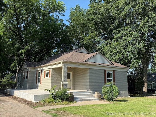2109 Delaware St, Muskogee, OK 74403 - view of front of house featuring a porch, brick siding, a front lawn, and roof with shingles