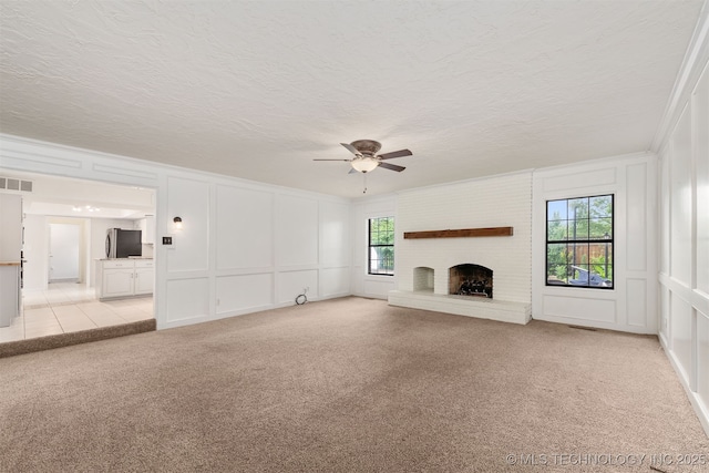3508 Kimberlea, Muskogee, OK 74403 - unfurnished living room featuring a decorative wall, light colored carpet, a ceiling fan, a brick fireplace, and a textured ceiling