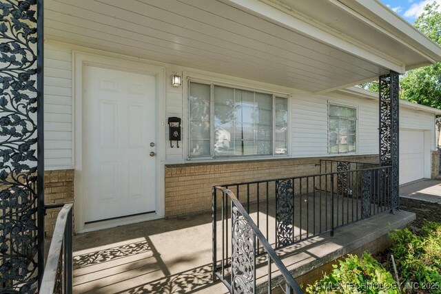 6210 E 17th St, Tulsa, OK 74112 - view of exterior entry with brick siding and an attached garage