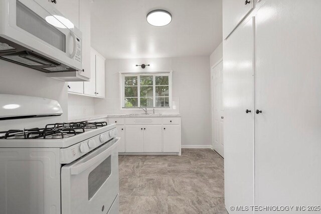 6210 E 17th St, Tulsa, OK 74112 - kitchen featuring white appliances, light countertops, white cabinetry, a sink, and baseboards