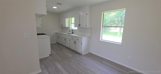 1405 S Cedar St, Bristow, OK 74010 - kitchen featuring a sink, white cabinetry, light countertops, light wood-style flooring, and baseboards