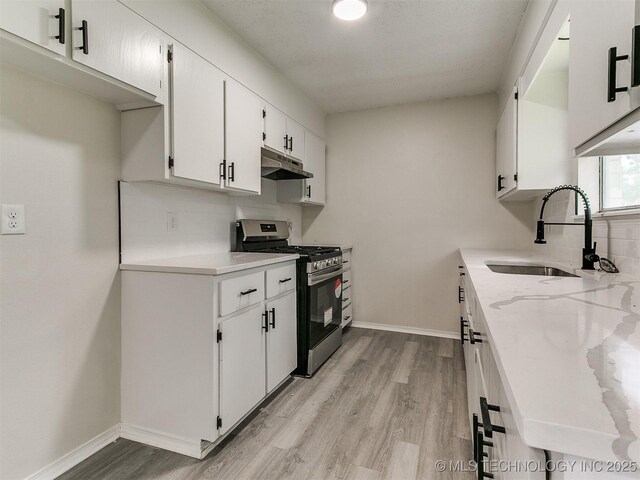 1405 S Cedar St, Bristow, OK 74010 - kitchen with stainless steel range with gas cooktop, light wood-style flooring, backsplash, and white cabinetry