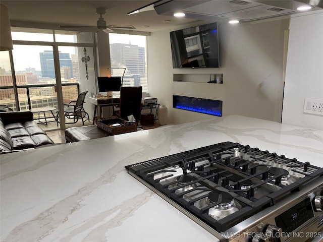 410 W 7th St Unit 1824, Tulsa, OK 74119 - kitchen featuring gas stove, a glass covered fireplace, light stone countertops, and a ceiling fan