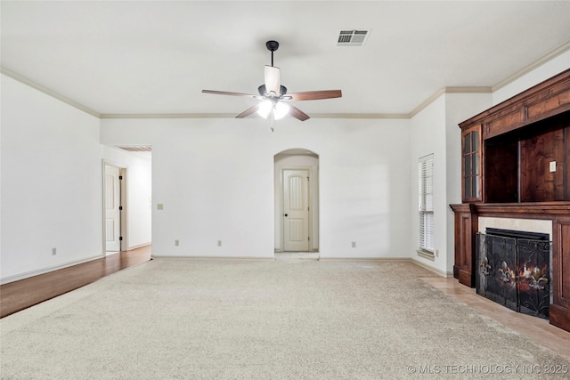 400 E Fargo St, Broken Arrow, OK 74012 - unfurnished living room featuring light colored carpet, ceiling fan, crown molding, arched walkways, and a fireplace with flush hearth