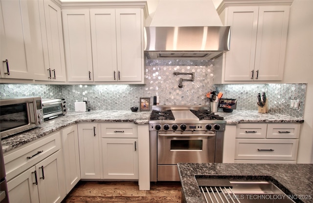 3704 River Bend Rd, Muskogee, OK 74403 - kitchen featuring appliances with stainless steel finishes, wall chimney exhaust hood, tasteful backsplash, and dark wood-type flooring