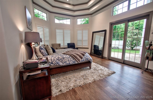 3704 River Bend Rd, Muskogee, OK 74403 - bedroom with ornamental molding, access to exterior, a towering ceiling, a tray ceiling, and wood finished floors