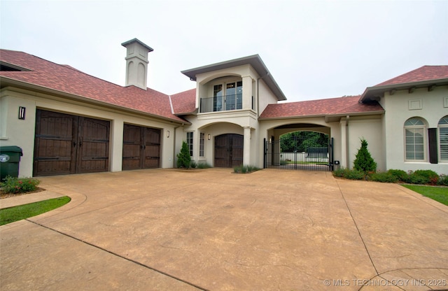 3704 River Bend Rd, Muskogee, OK 74403 - mediterranean / spanish-style home featuring driveway, stucco siding, a balcony, a gate, and an attached garage