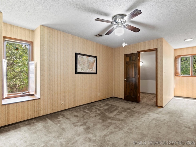 639 Oakridge Dr, Bartlesville, OK 74006 - unfurnished bedroom with carpet floors, wallpapered walls, a textured ceiling, and ceiling fan