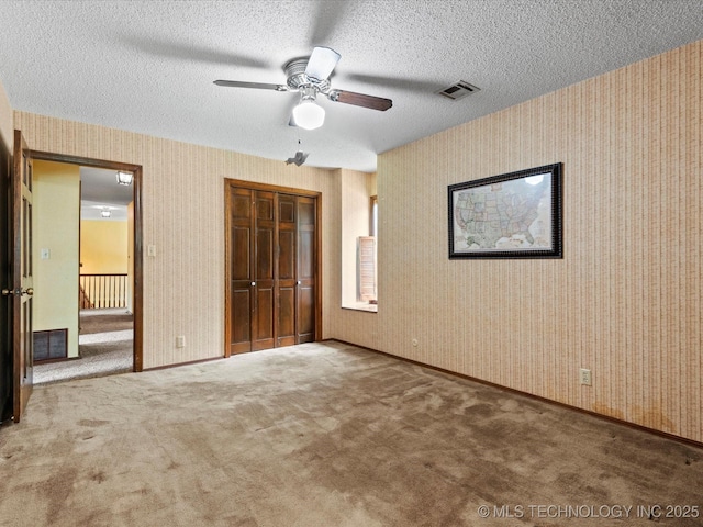 639 Oakridge Dr, Bartlesville, OK 74006 - unfurnished bedroom with carpet flooring, a closet, wallpapered walls, a textured ceiling, and ceiling fan