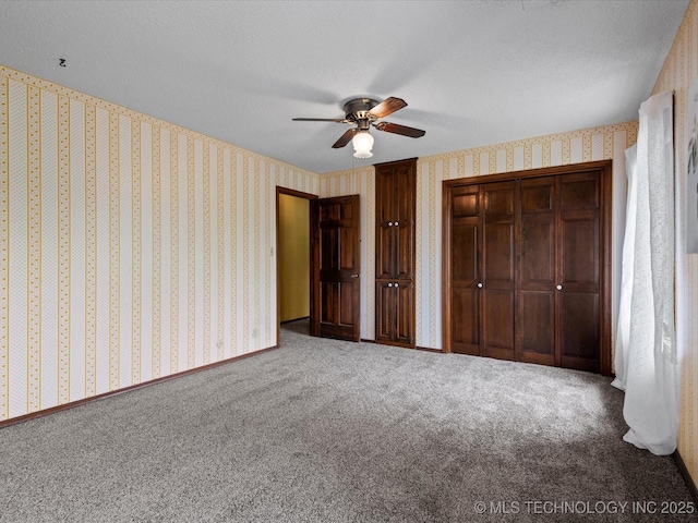 639 Oakridge Dr, Bartlesville, OK 74006 - unfurnished bedroom featuring wallpapered walls, carpet flooring, two closets, and a ceiling fan