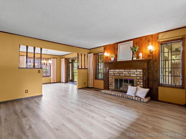 639 Oakridge Dr, Bartlesville, OK 74006 - unfurnished living room with a textured ceiling, a fireplace, wood finished floors, and a chandelier