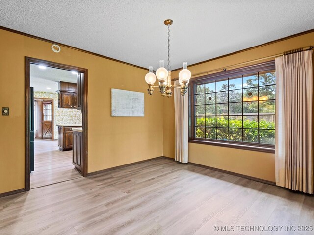 639 Oakridge Dr, Bartlesville, OK 74006 - unfurnished dining area featuring light wood-style floors, crown molding, a chandelier, and a textured ceiling