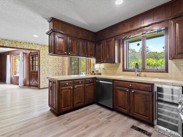 639 Oakridge Dr, Bartlesville, OK 74006 - kitchen featuring wine cooler, dishwasher, tile countertops, light wood-style floors, and a textured ceiling