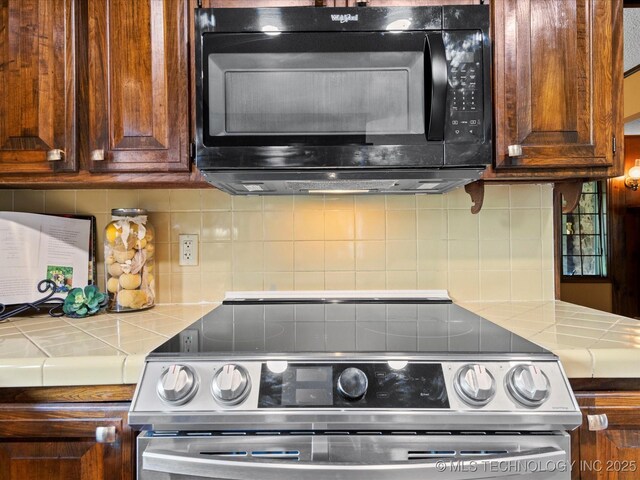 639 Oakridge Dr, Bartlesville, OK 74006 - kitchen with black microwave, stainless steel electric range, tile counters, and backsplash