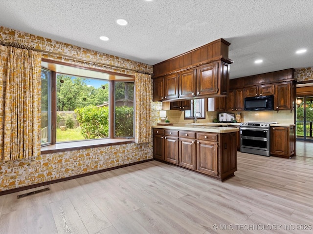 639 Oakridge Dr, Bartlesville, OK 74006 - kitchen featuring range with two ovens, black microwave, light countertops, a textured ceiling, and light wood-style floors