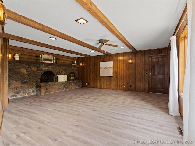 639 Oakridge Dr, Bartlesville, OK 74006 - unfurnished living room with light wood finished floors, ceiling fan, beam ceiling, a fireplace, and wooden walls