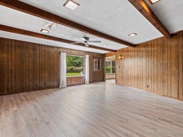 639 Oakridge Dr, Bartlesville, OK 74006 - unfurnished living room with beamed ceiling, wood walls, light wood finished floors, a ceiling fan, and a textured ceiling