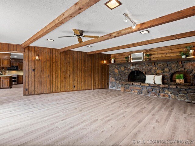639 Oakridge Dr, Bartlesville, OK 74006 - unfurnished living room featuring beamed ceiling, a fireplace, wooden walls, light wood-style floors, and a ceiling fan