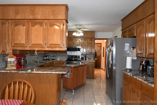 990 Turney Ave, Tahlequah, OK 74464 - kitchen with stainless steel appliances, brown cabinetry, decorative backsplash, and light tile patterned flooring
