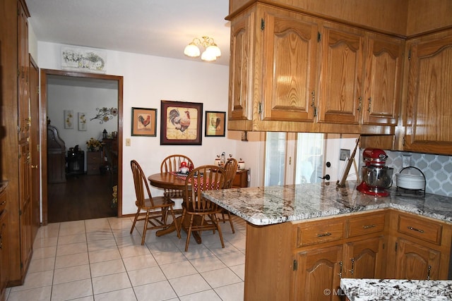 990 Turney Ave, Tahlequah, OK 74464 - kitchen with a peninsula, brown cabinets, light tile patterned flooring, backsplash, and light stone counters