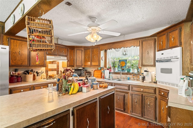 800 N Hwy 10, Gore, OK 74435 - kitchen featuring oven, a sink, under cabinet range hood, light countertops, and a textured ceiling