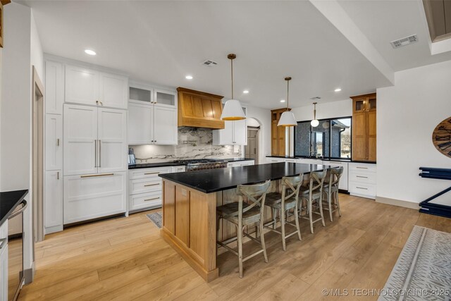 35795 E 231st St S, Porter, OK 74454 - kitchen with dark countertops, tasteful backsplash, a spacious island, glass insert cabinets, and light wood-type flooring