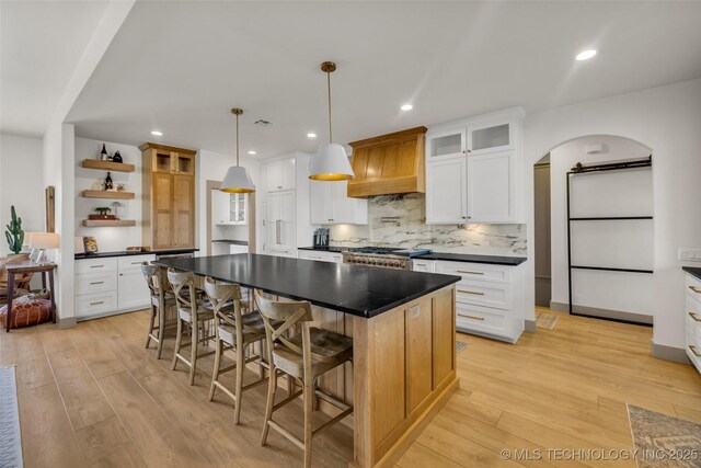 35795 E 231st St S, Porter, OK 74454 - kitchen featuring open shelves, dark countertops, light wood-style floors, premium range hood, and arched walkways