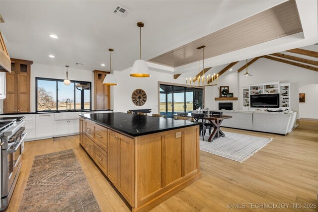 35795 E 231st St S, Porter, OK 74454 - kitchen featuring range with two ovens, a kitchen island, a fireplace, light wood-style floors, and decorative light fixtures